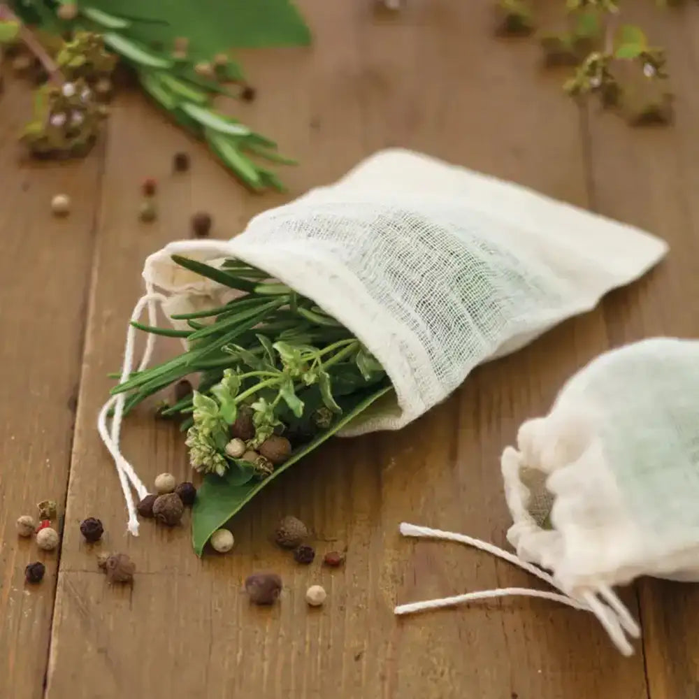 Herbal bags with green leaves and peppercorns on a wooden surface