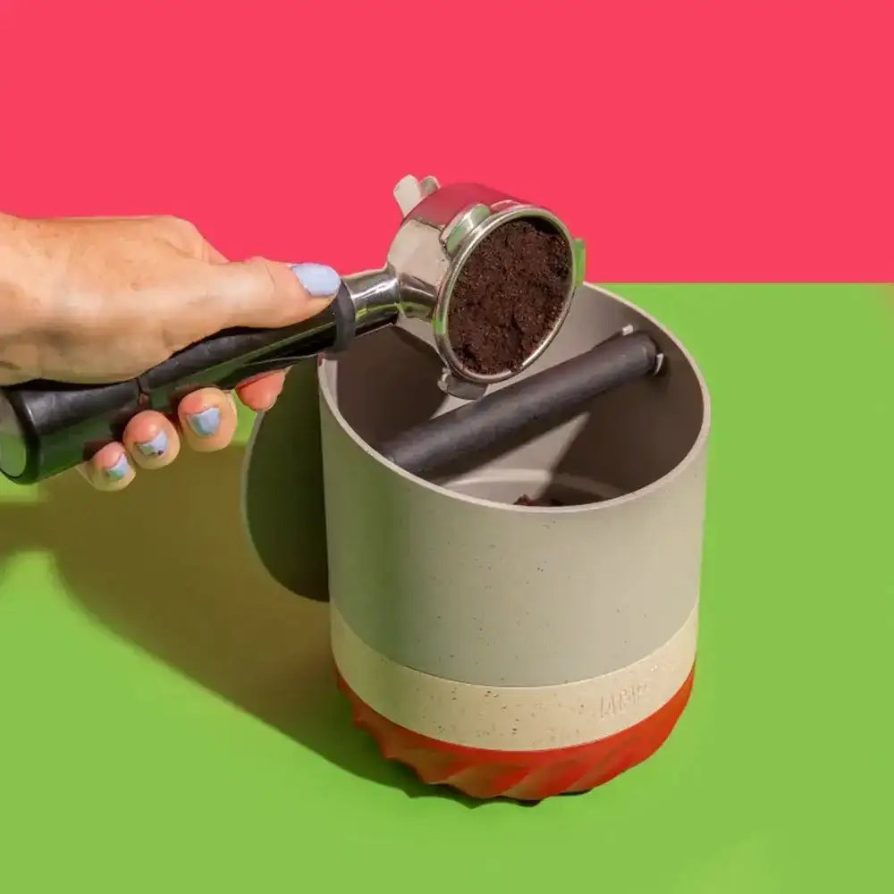 Hand using a manual coffee grinder with a colorful background