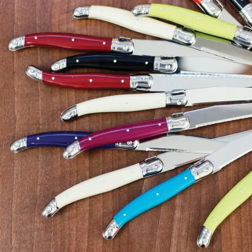 Set of colorful knives with wooden handles on a wooden surface