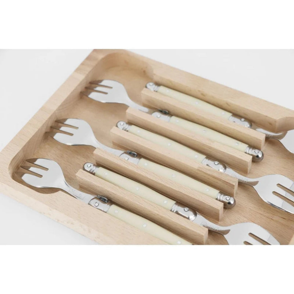 A set of six utensils with cream-colored handles and silver metal tines, organized in a light natural wood storage tray on a white background.