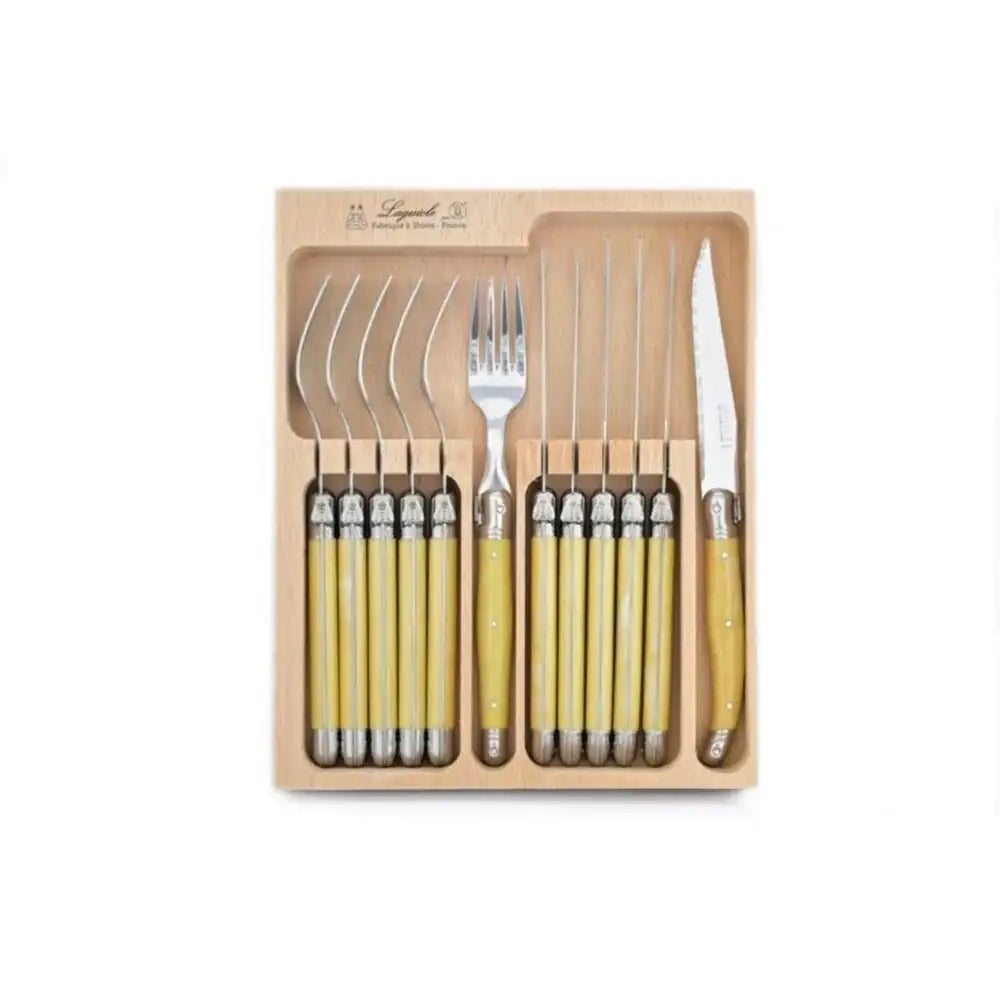 Set of cutlery with yellow handles in a wooden box on a white background