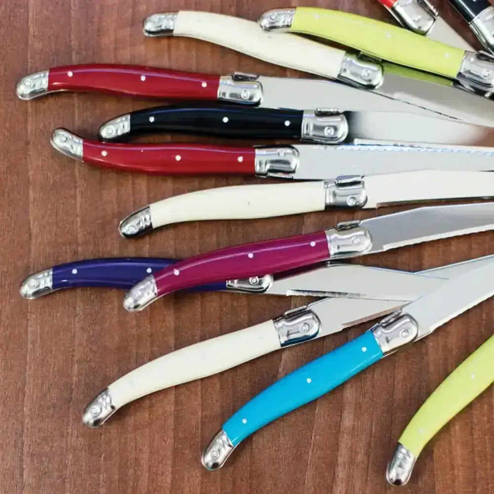 Set of colorful knives on a wooden surface