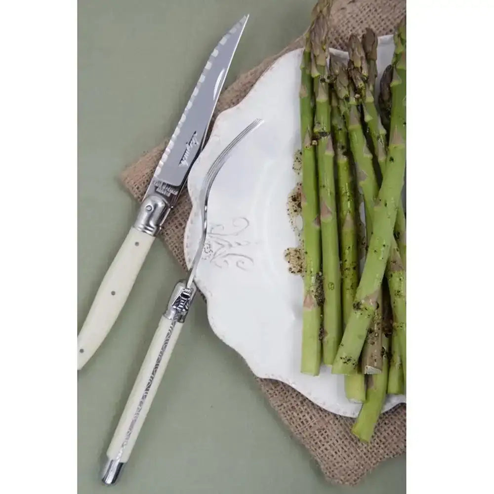 Set of steak knives with decorative handles on a plate with asparagus.