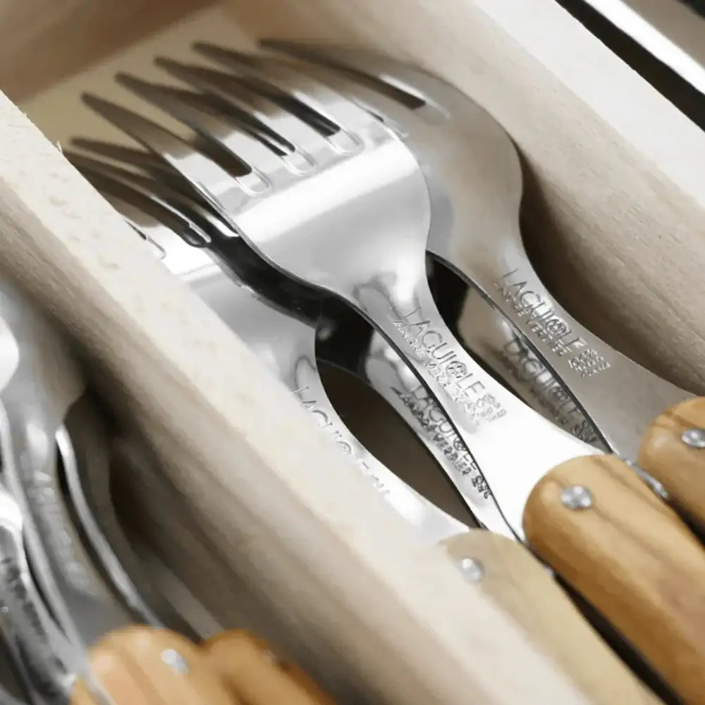 Set of silver forks with wooden handles in a wooden holder
