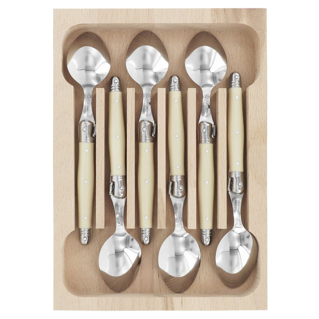 Set of silver spoons with beige handles in a wooden tray