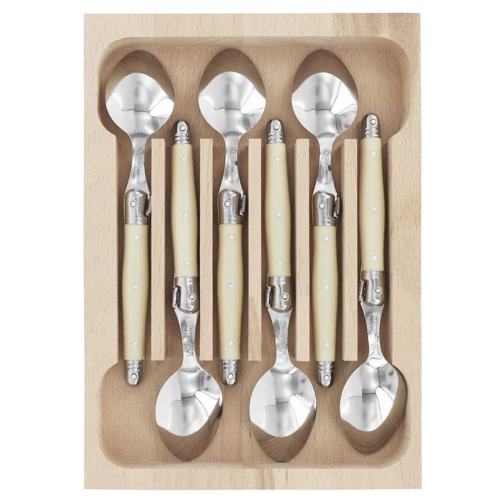 Set of silver spoons with beige handles in a wooden tray