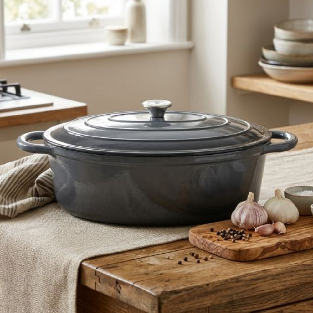 Grey cast iron Dutch oven on a wooden kitchen counter with ingredients and a window in the background.