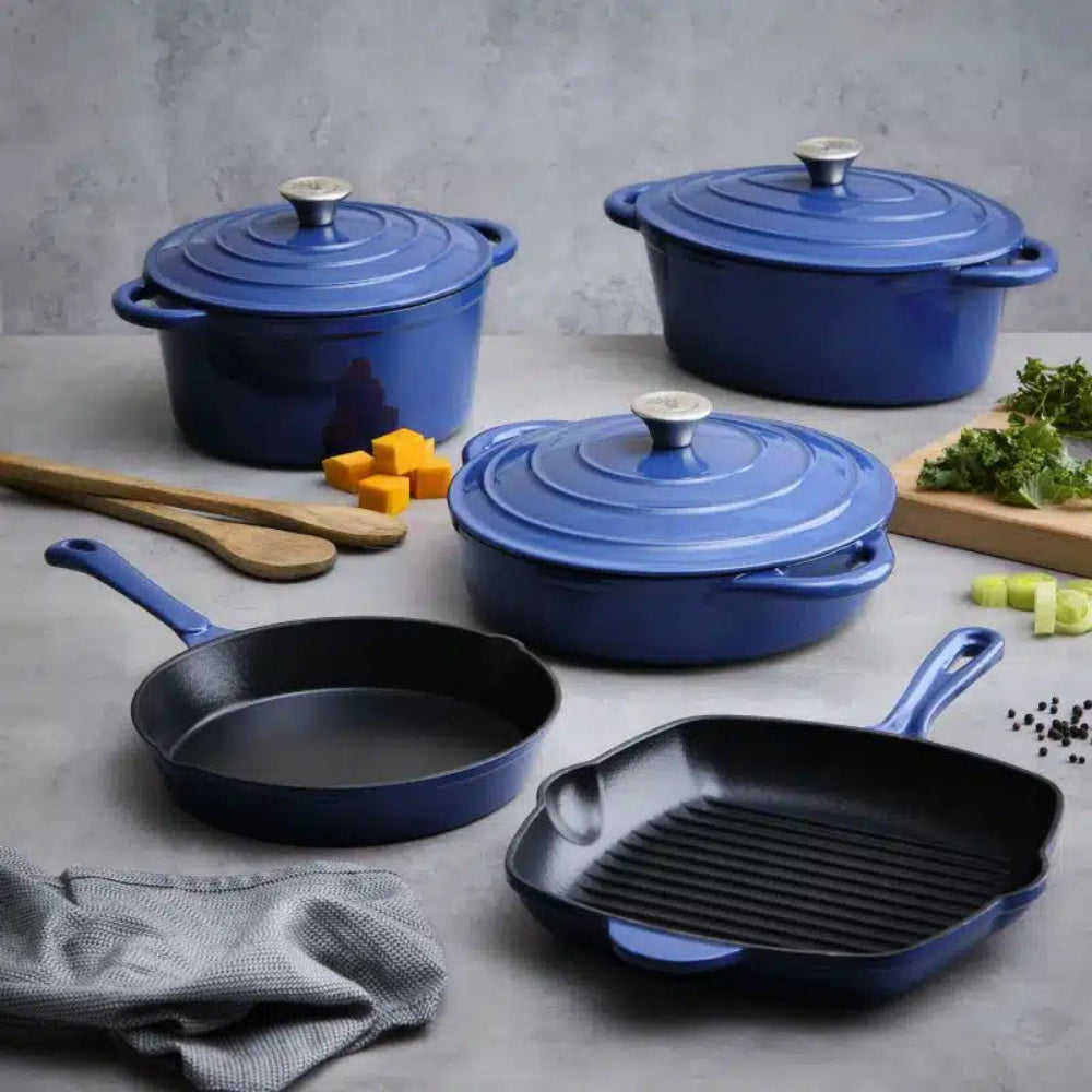 Set of blue cast iron cookware including pots and pans on a gray surface with ingredients.