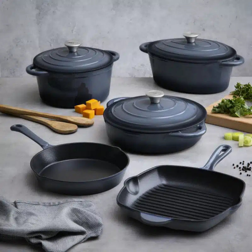 Set of grey cookware including pots, pans, and a grill on a gray surface.
