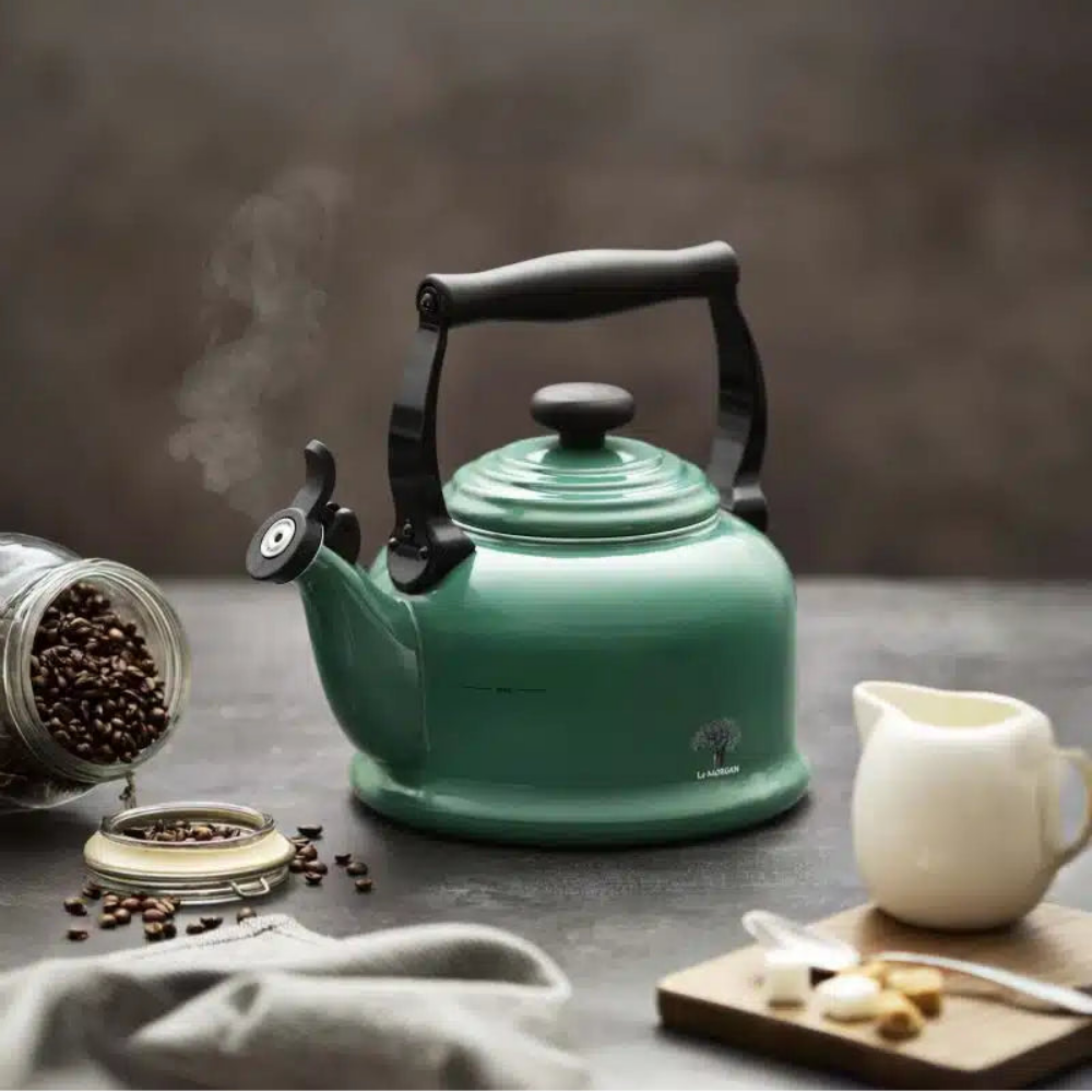 Dark green kettle on a dark surface with coffee beans and a milk jug in the background.