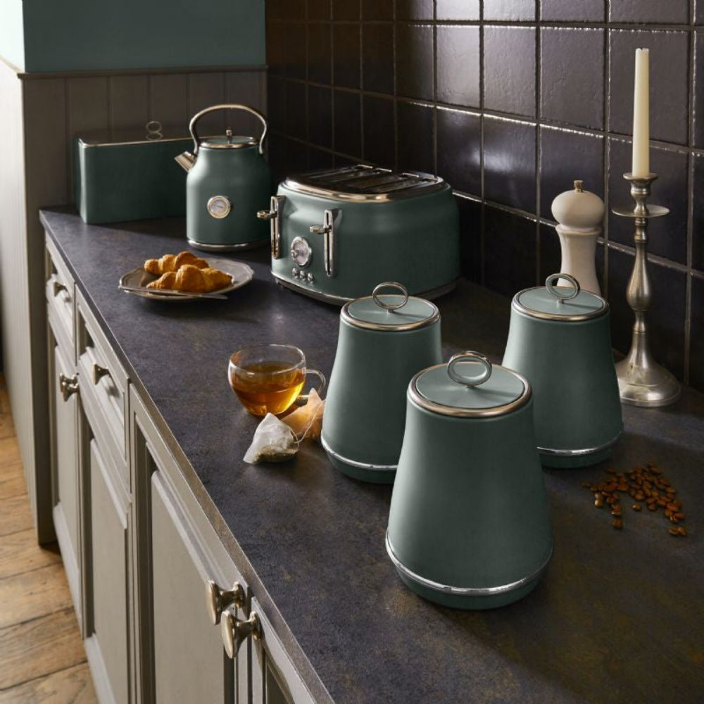 Green kitchen appliances including a kettle, toaster, and canisters on a dark countertop.
