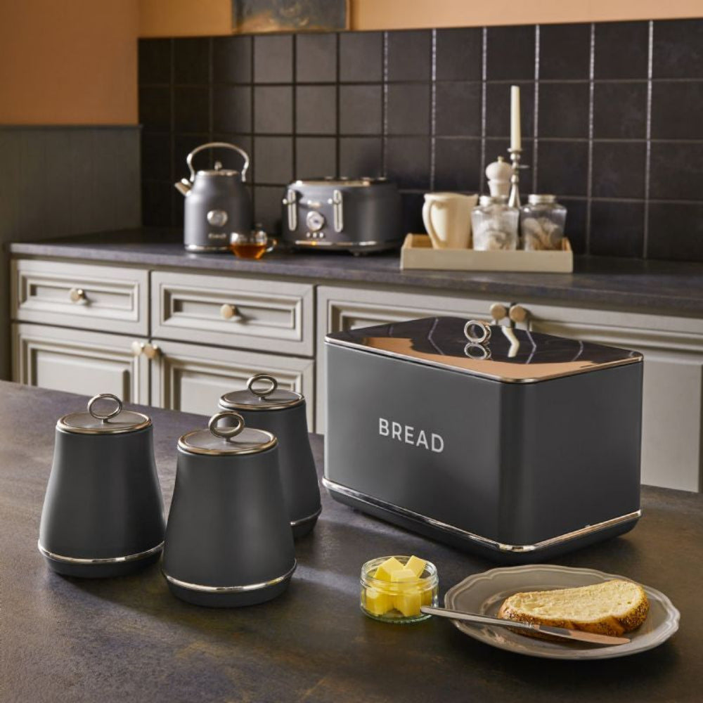 Kitchen scene with a bread bin, canisters, and a plate of toast on a countertop.