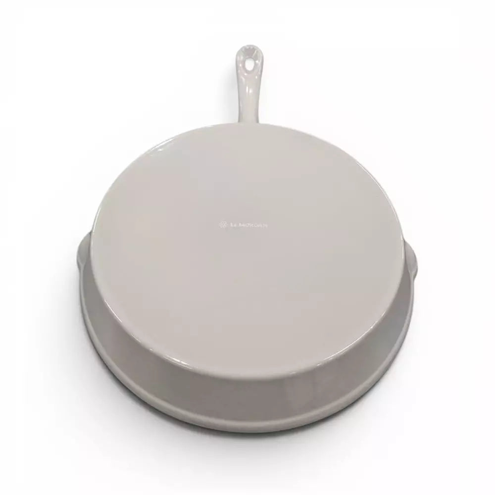 Beige enamel cast iron frying pan with a beige handle on a white background