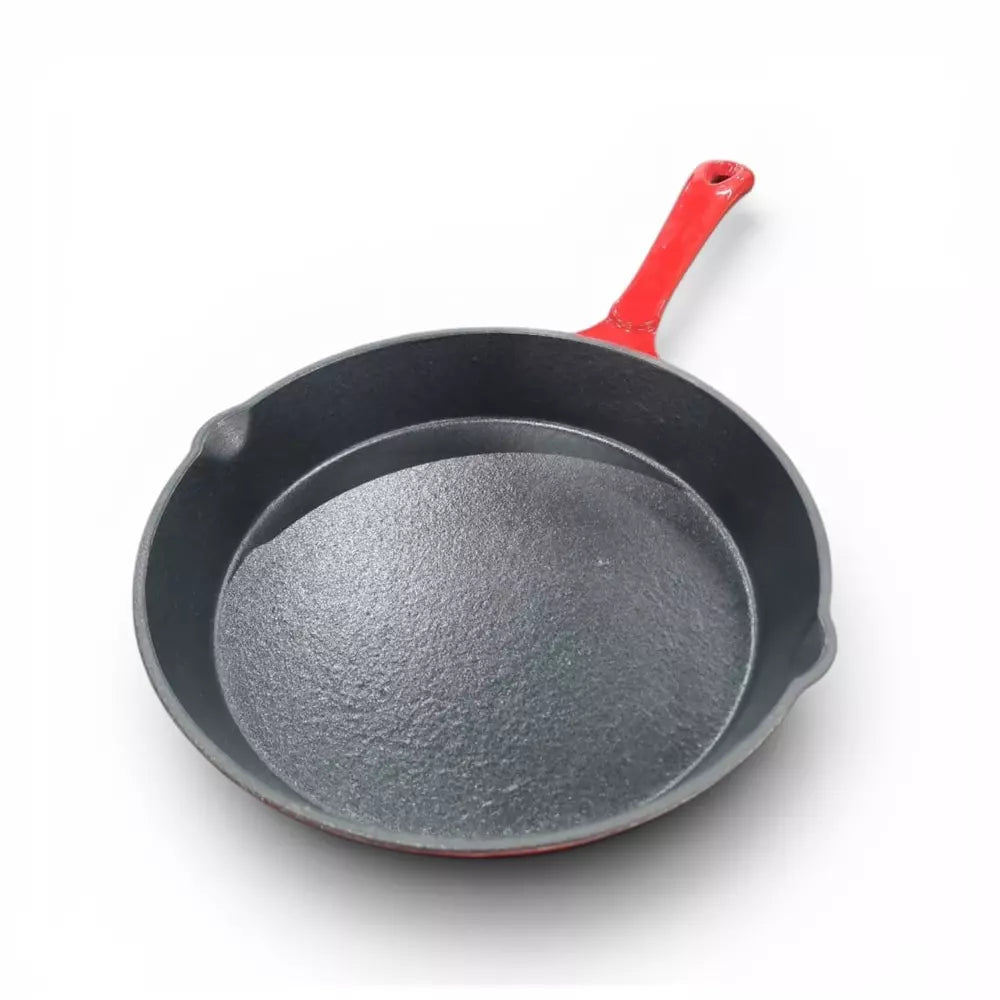 Red cast iron frying pan with a red handle on a white background