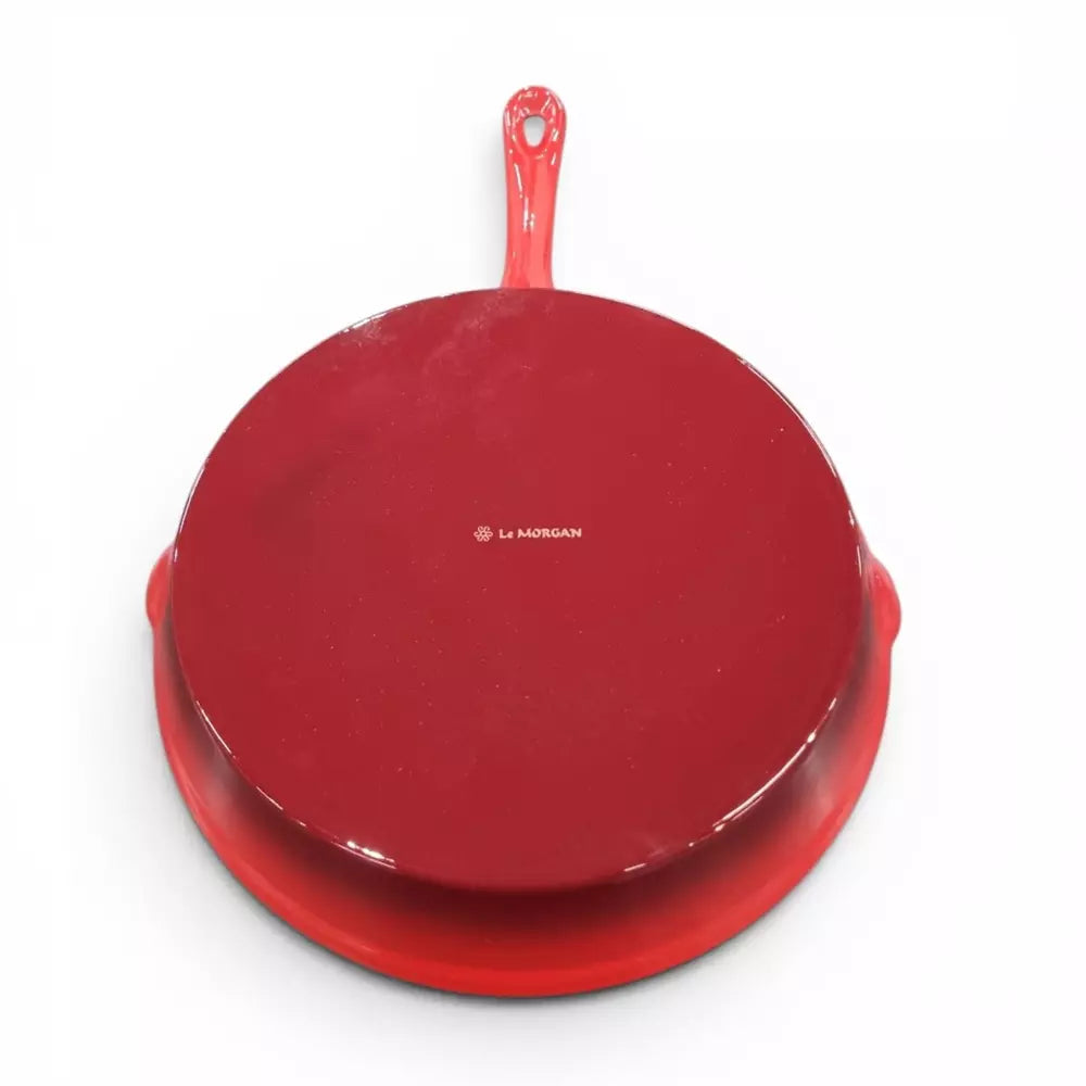 Red cast iron frying pan with a red handle on a white background
