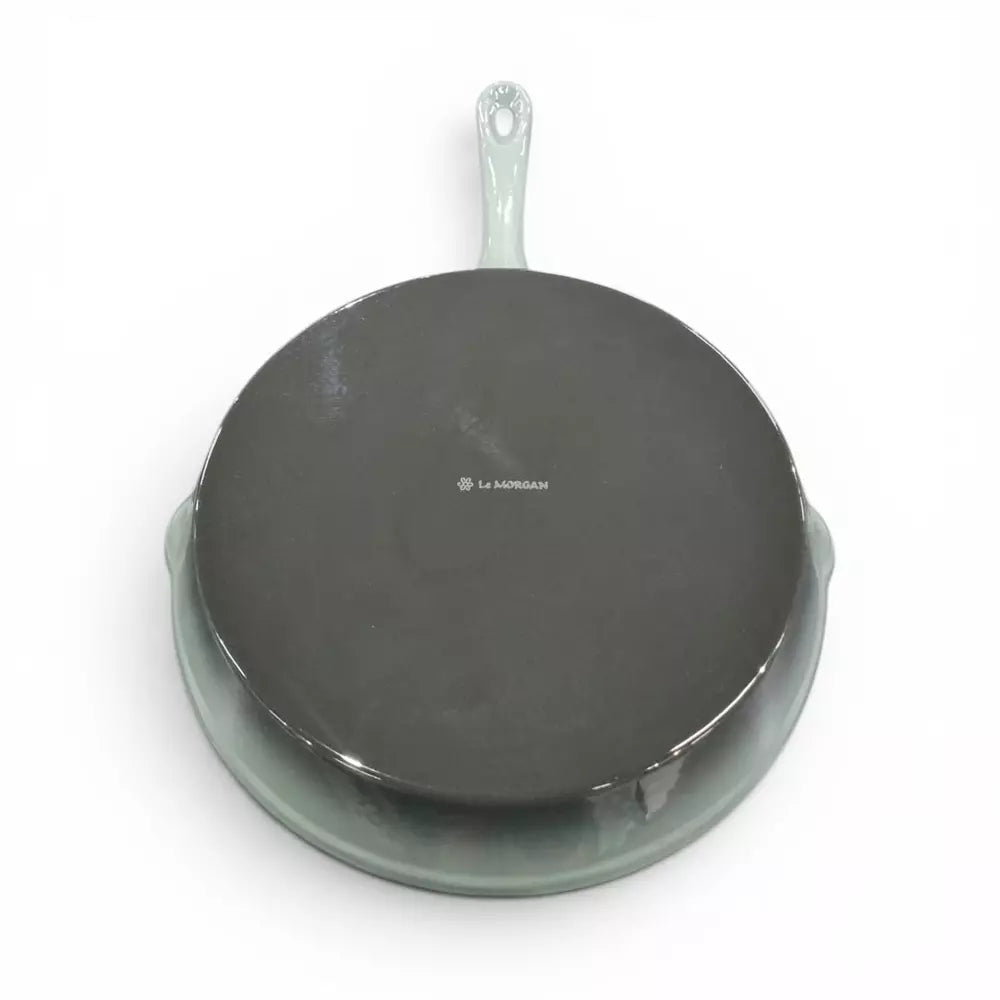 Green cast iron frying pan with a green handle on a white background