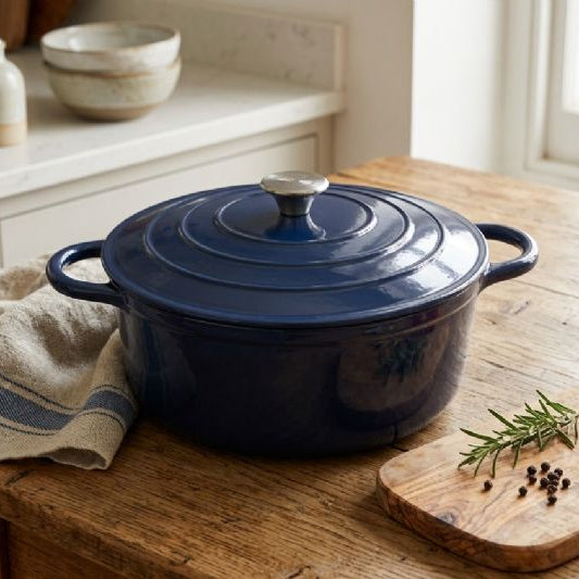 Blue enameled cast iron Dutch oven on a wooden surface with a window in the background