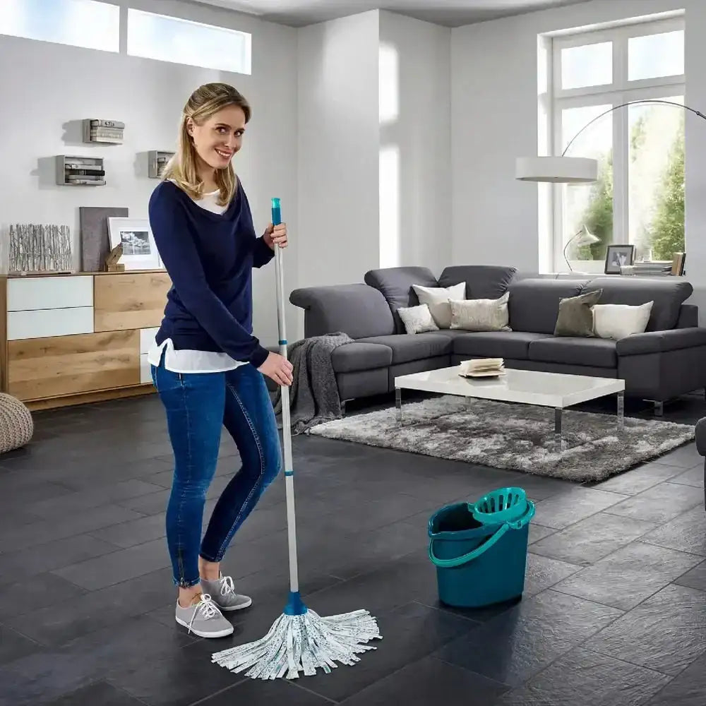 Woman cleaning a living room with a mop and bucket.