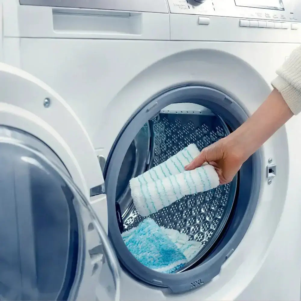 Person cleaning inside a washing machine with a blue and white towel.