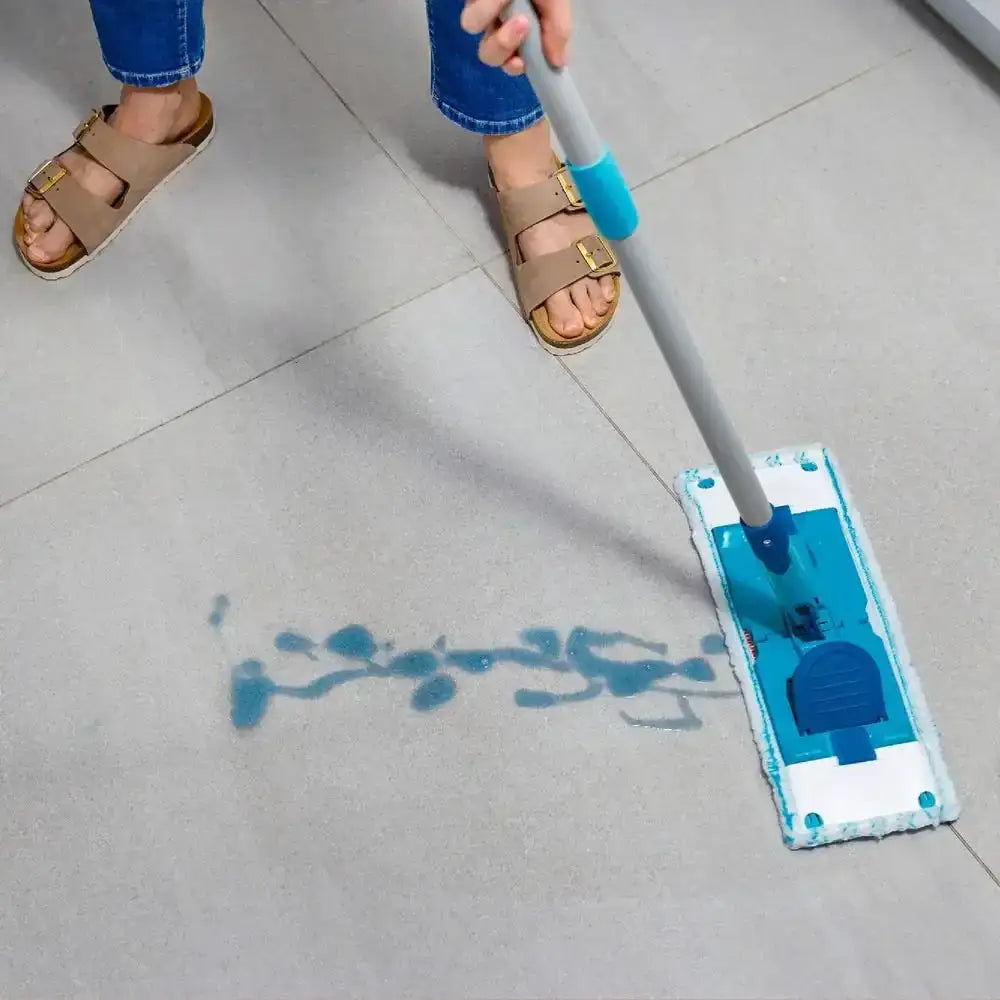 Person cleaning a tiled floor with a blue and gray mop.
