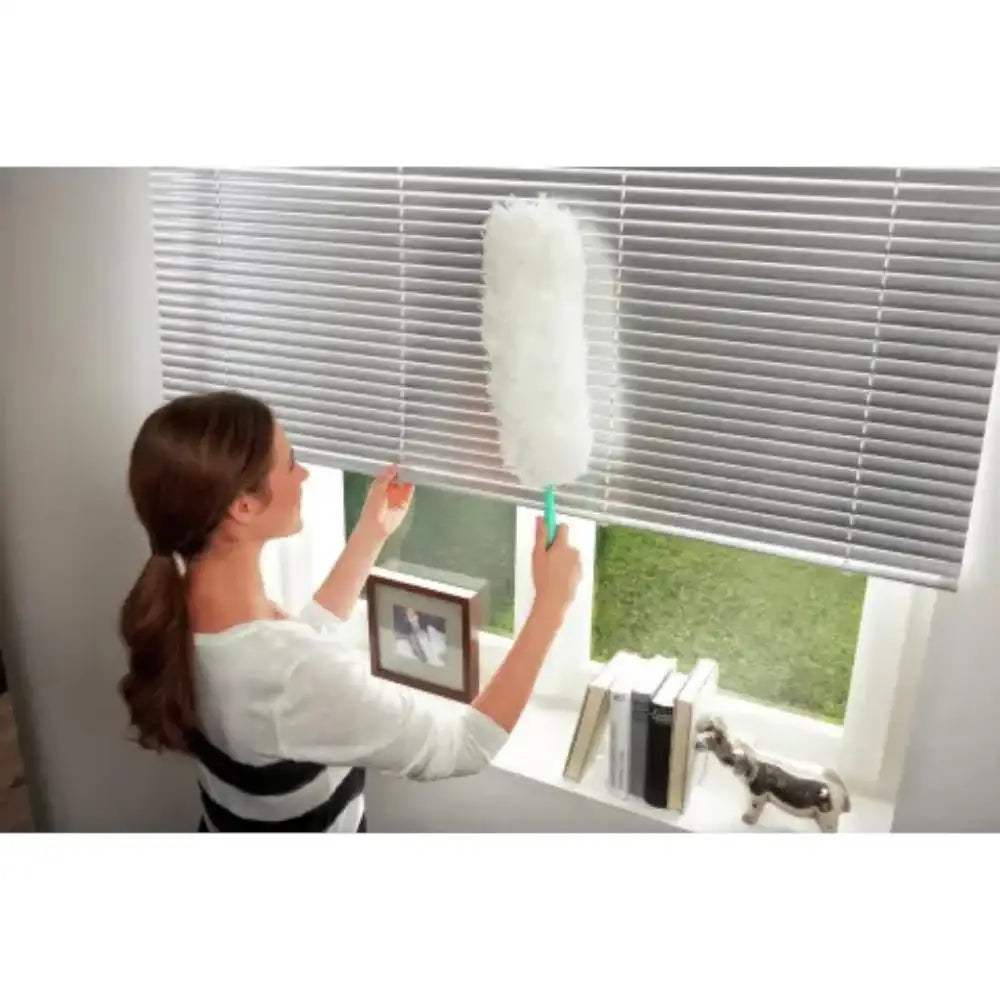 Person cleaning window blinds with a duster