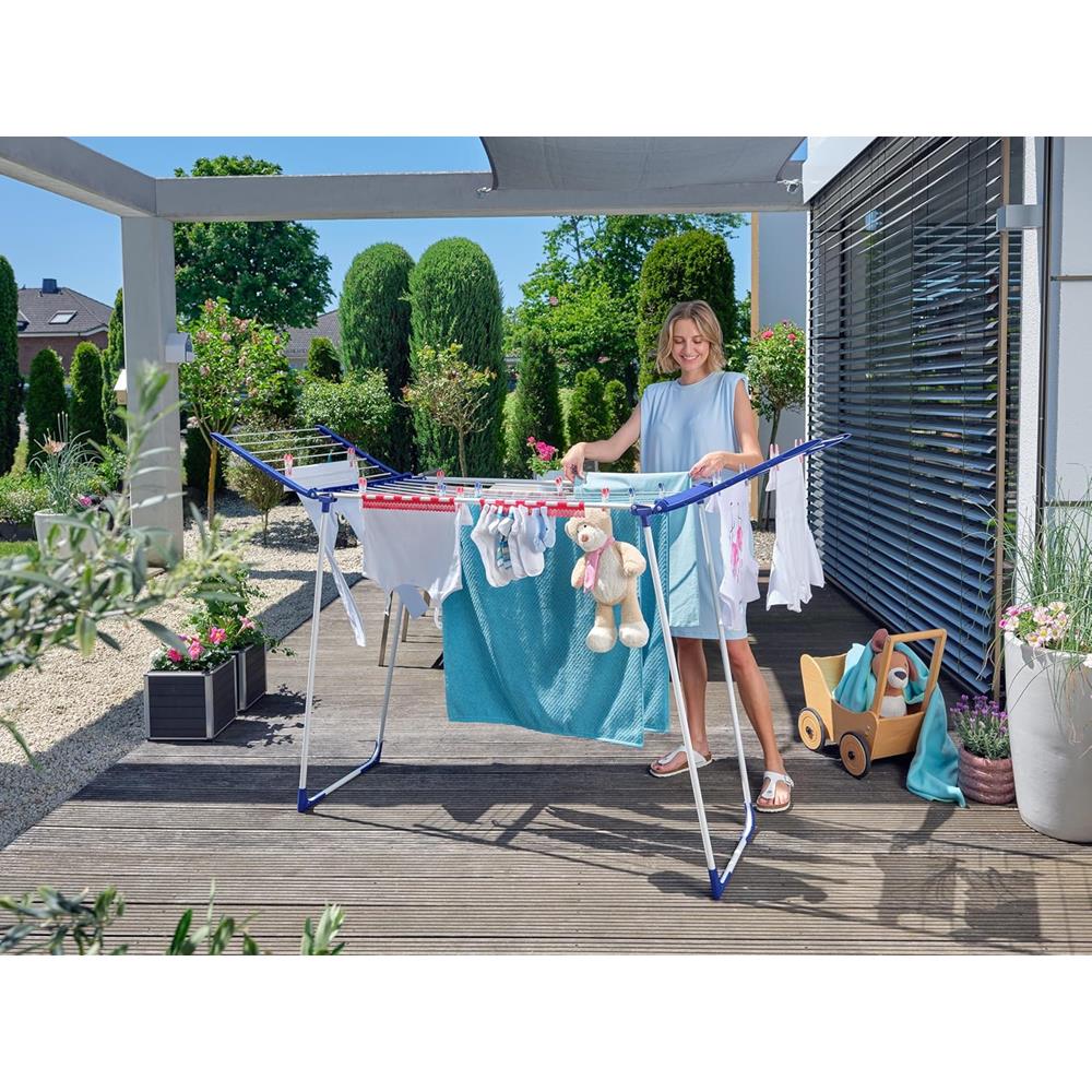 Woman hanging clothes on an outdoor drying rack with a garden background