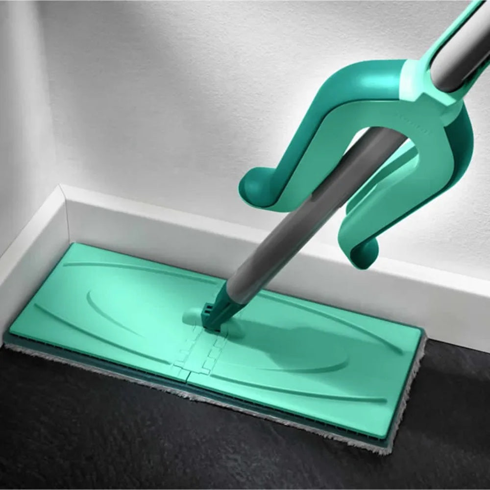 Green floor cleaning tool with a flat pad and handle cleaning a floor.