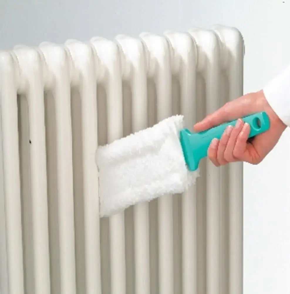 Hand using a teal radiator cleaning brush with white bristle pad on a radiator.