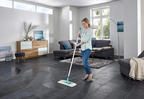 Woman cleaning a modern living room with a mop.