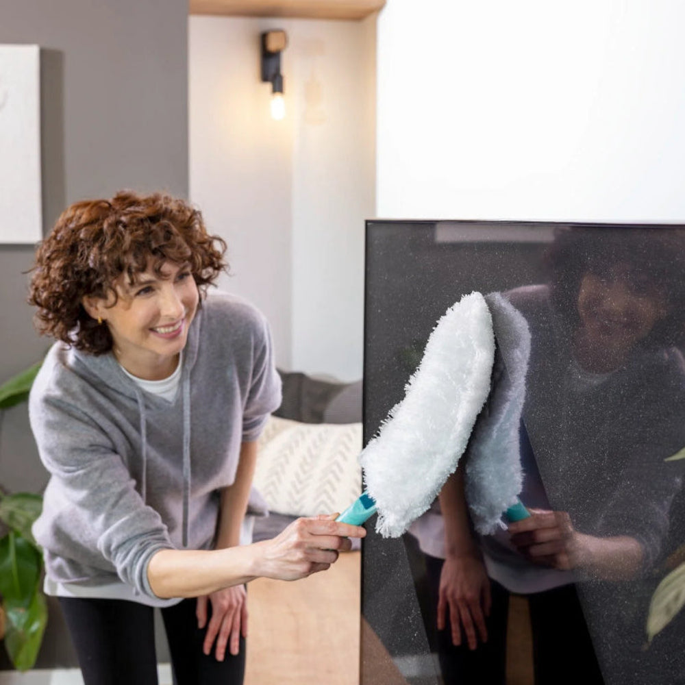 Woman dusting a TV screen with a large handheld duster 