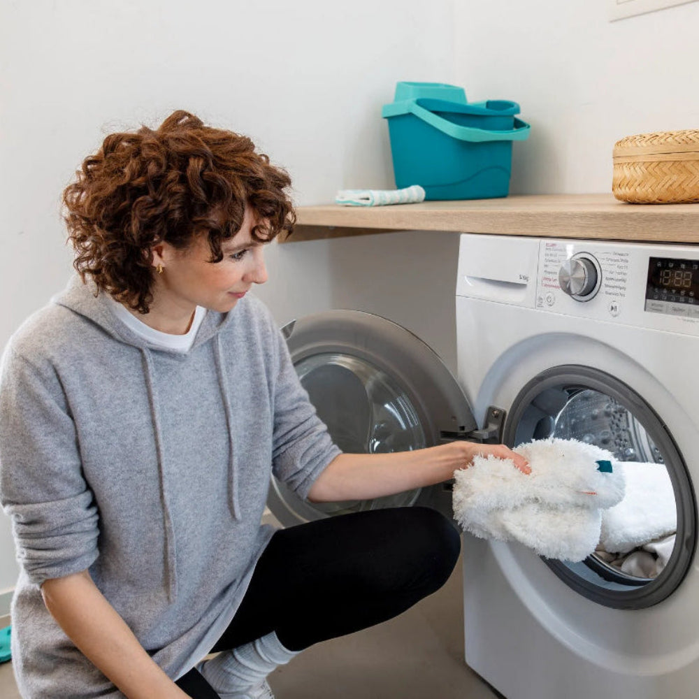 Woman placing a soft blanket into a washing machine