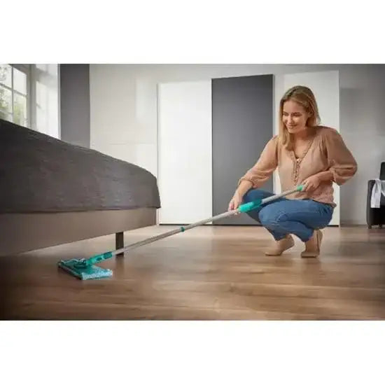 Woman cleaning a wooden floor with a mop in a bedroom.