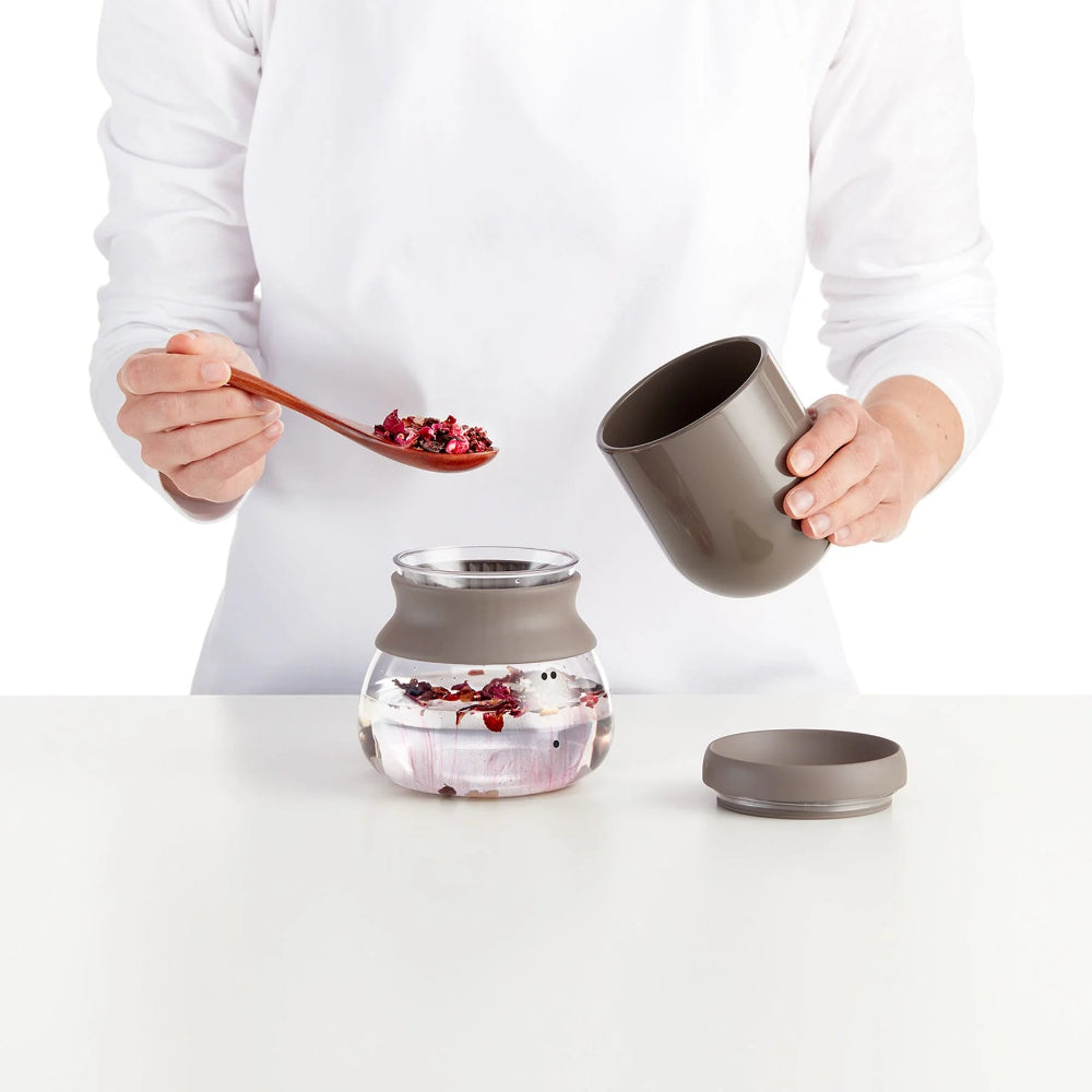 Person adding loose tea leaves to a glass container 