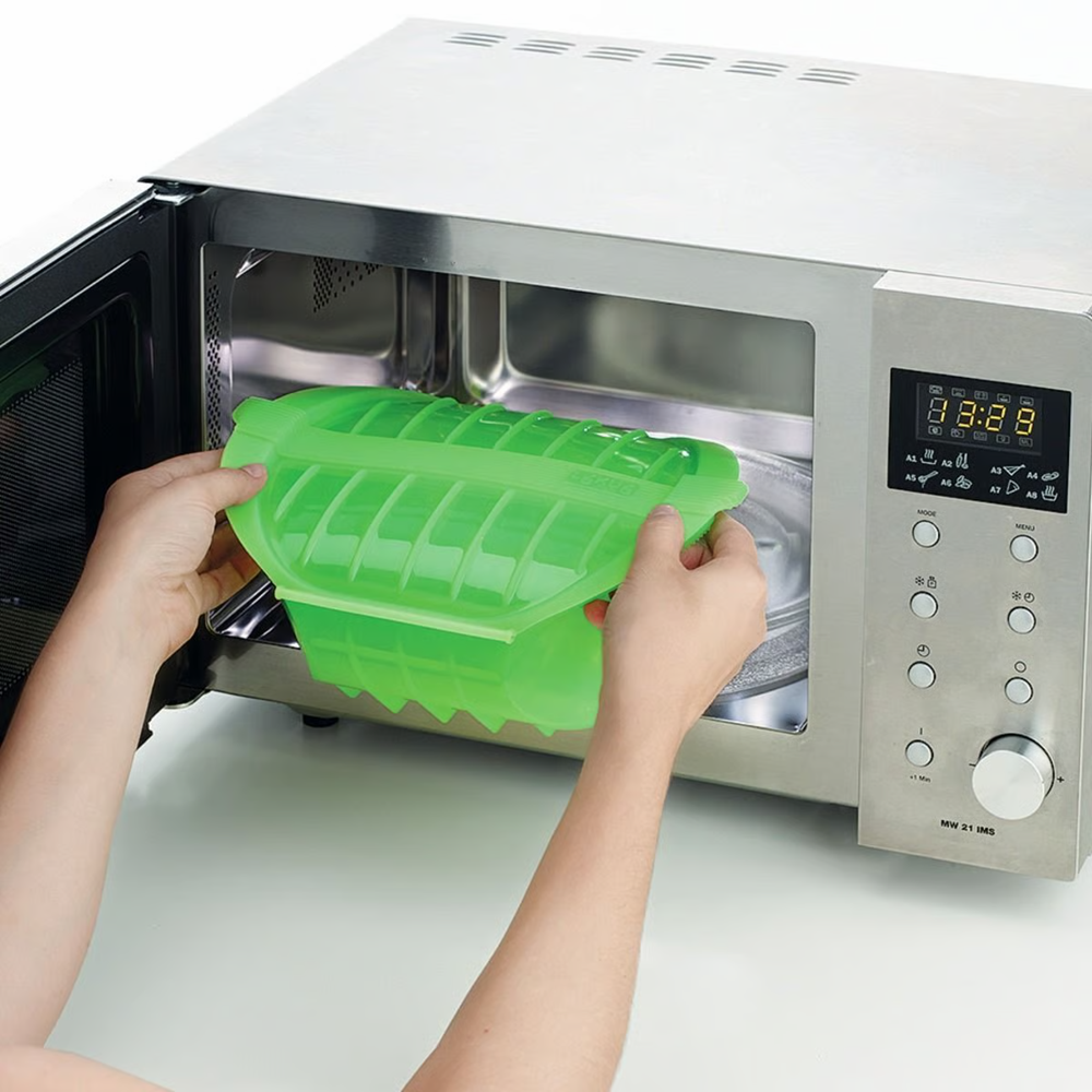 Person placing a steam cooker inside a microwave 
