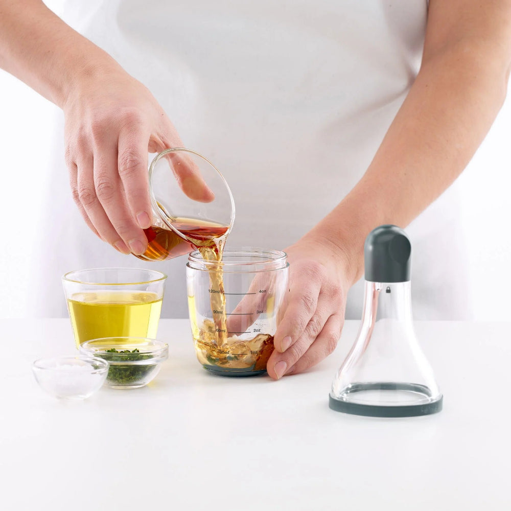 Person pouring oil into a measuring cup