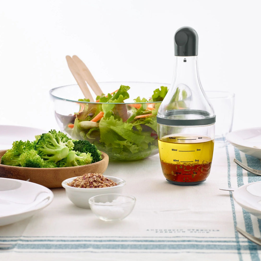 Dressing shaker on a table with salad in the background