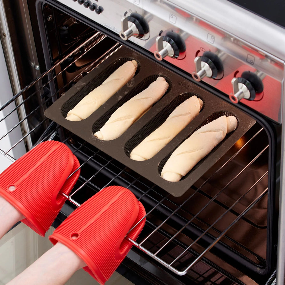 Person placing a loaf pan into an oven with red oven gloves