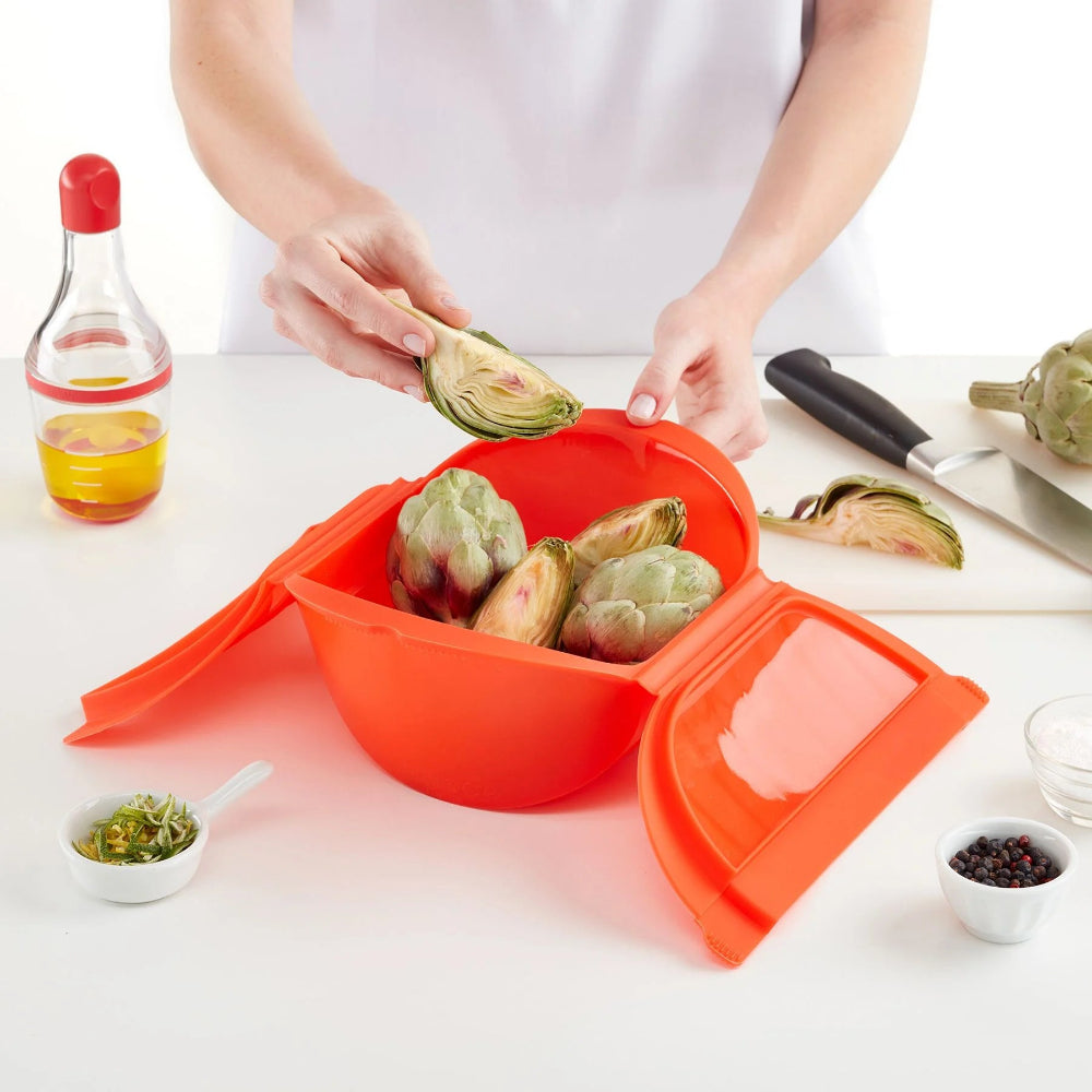 Person placing vegetables inside a microwave steamer 