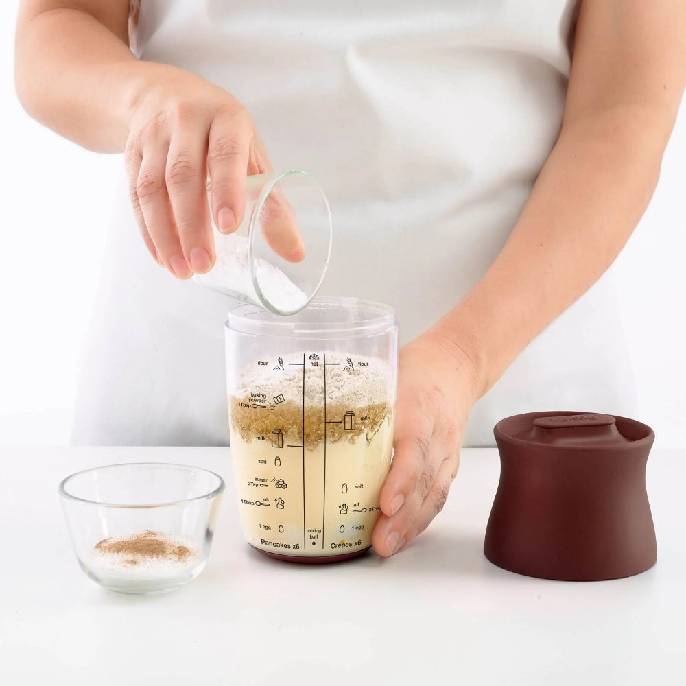 Person adding ingredients to a jar 