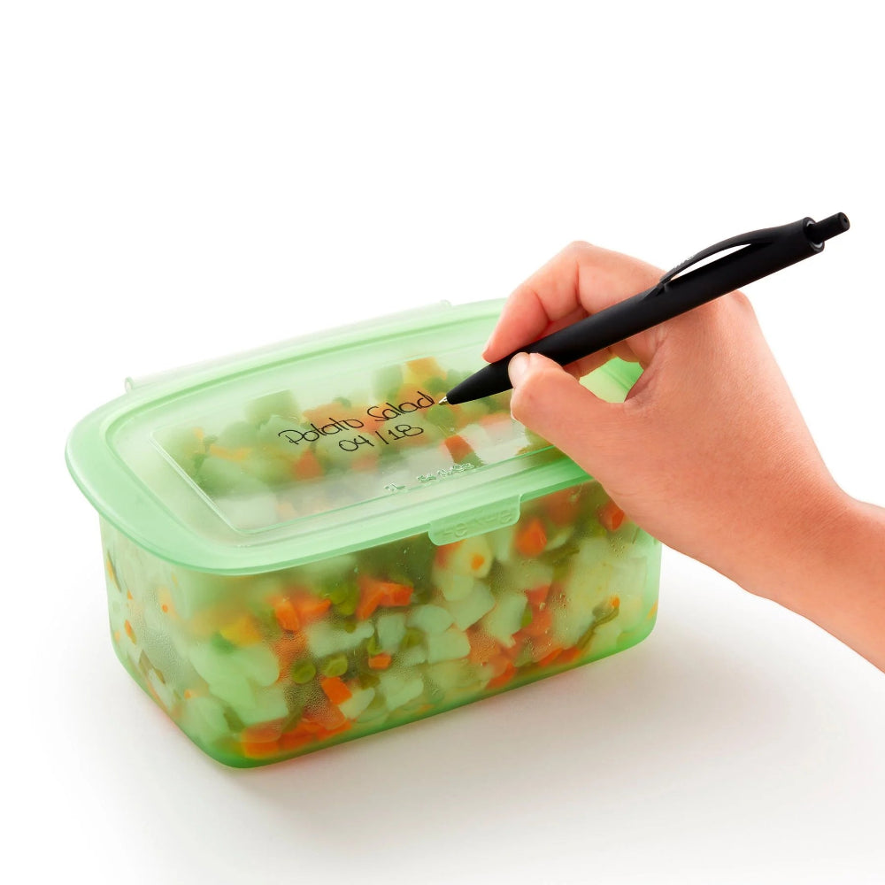 Person labelling "Potato Salad" on a green container 