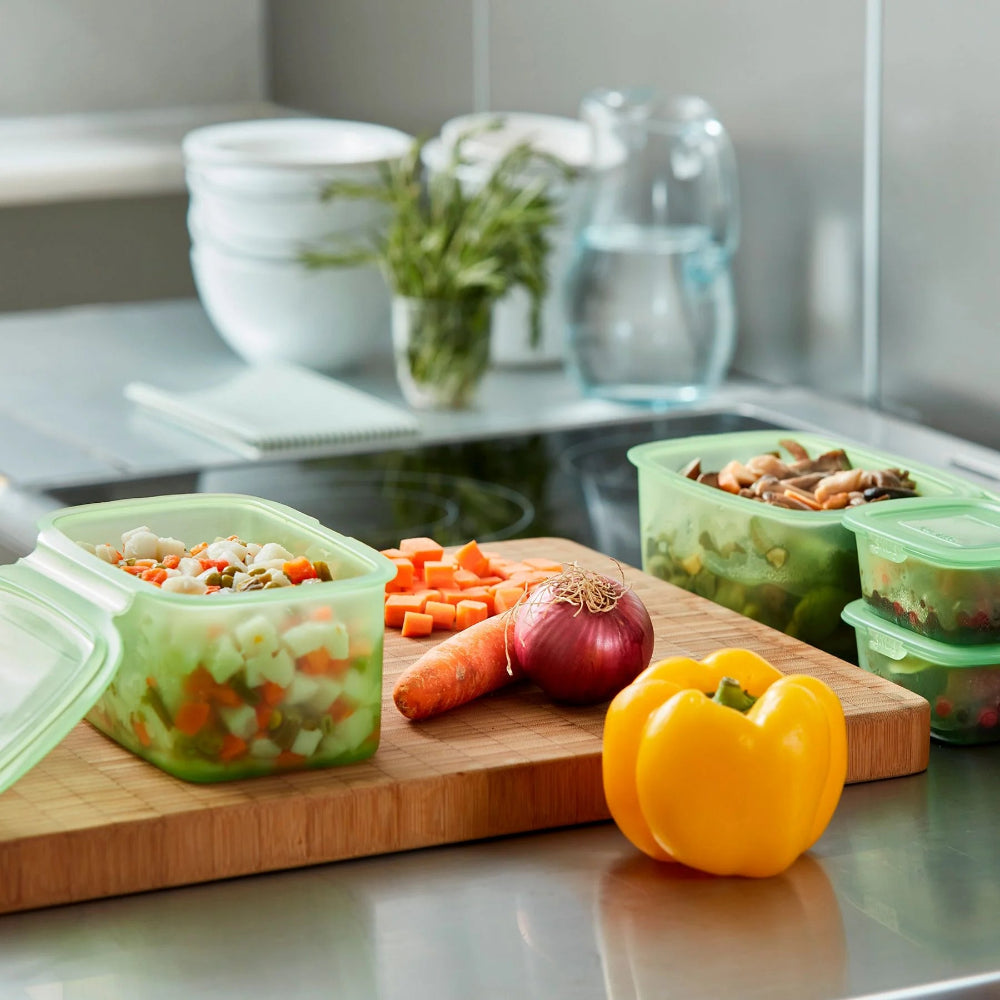 Kitchen counter with chopped vegetables and green containers 