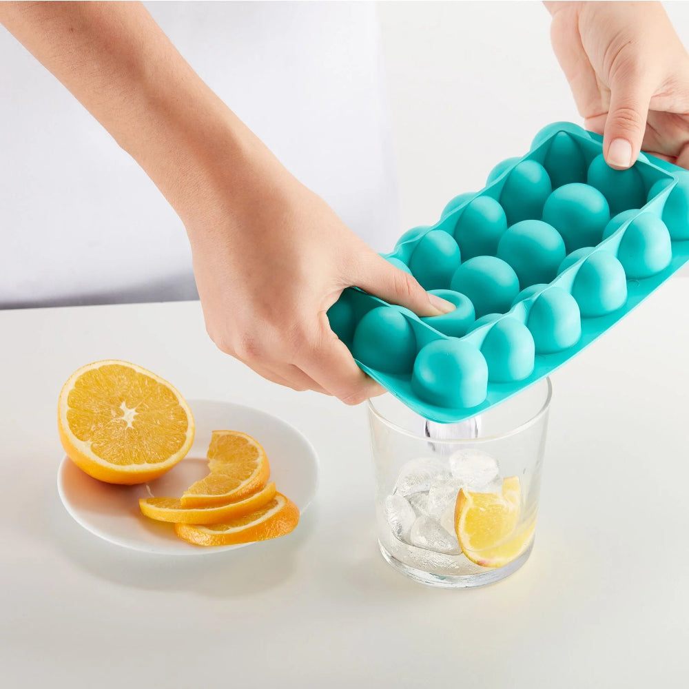 Person adding ice to a glass using a silicone ice tray