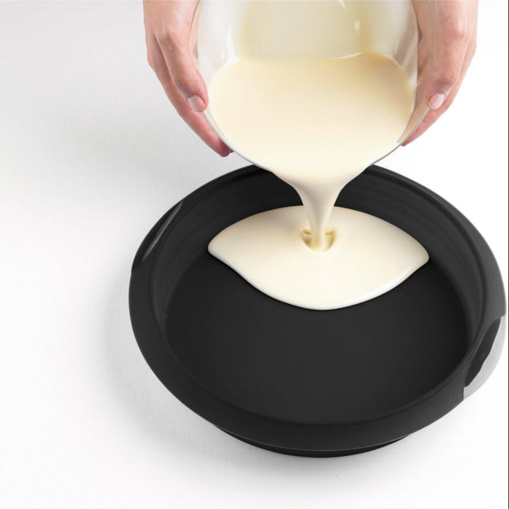 Person pouring batter into a round cake pan