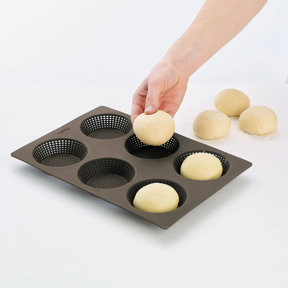Person adding dough balls to a baking tray with a white background