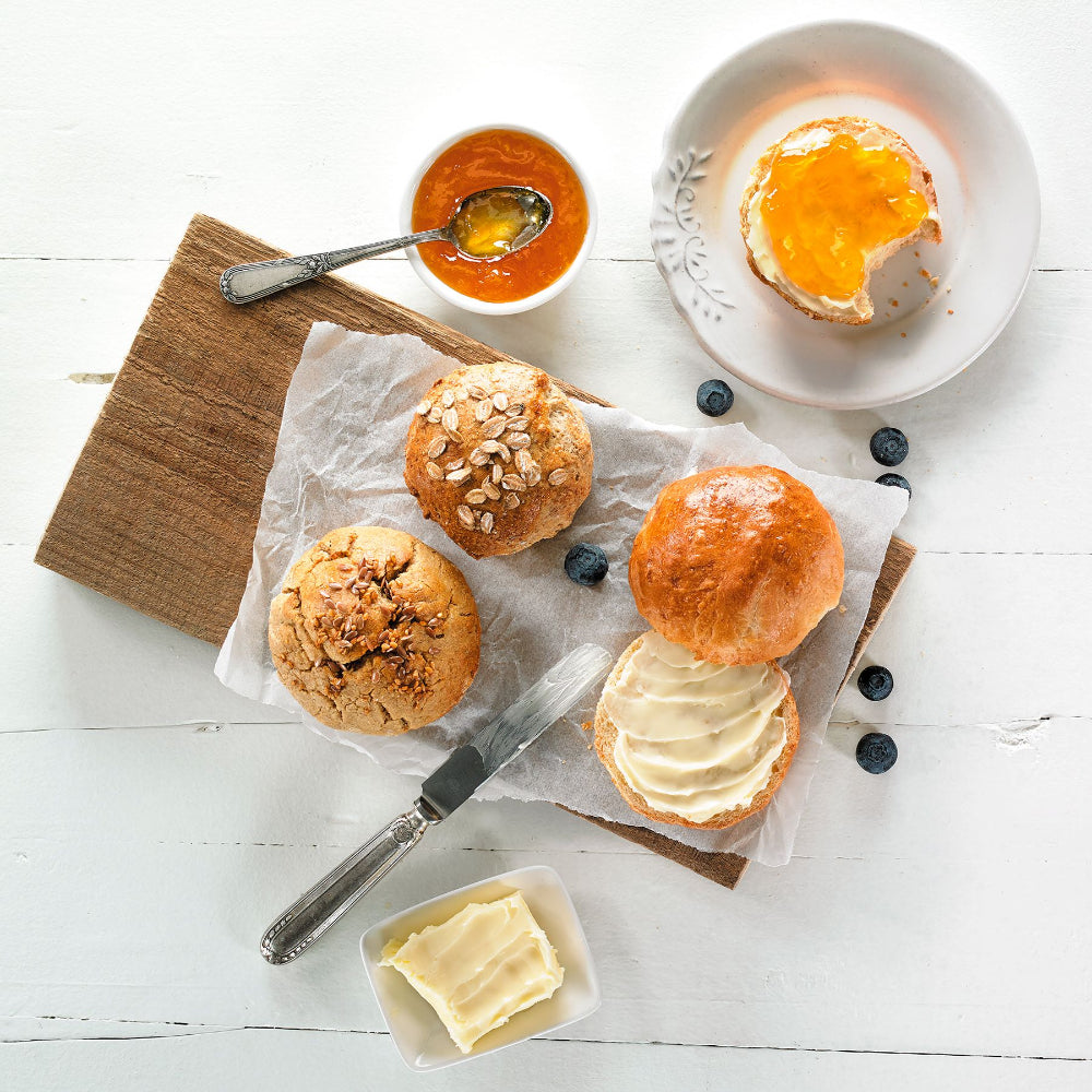Bread rolls with butter and jam on a wooden cutting board 
