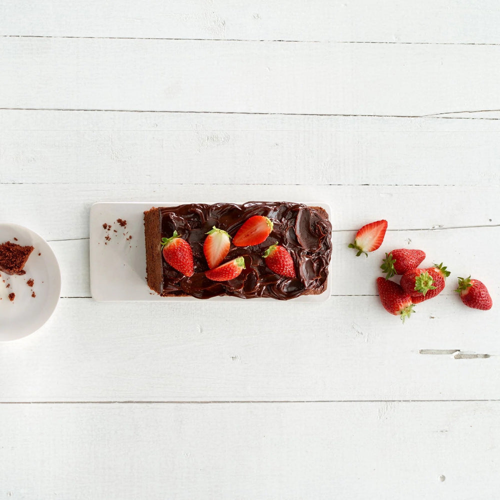Chocolate cake with strawberries on a white wooden surface 