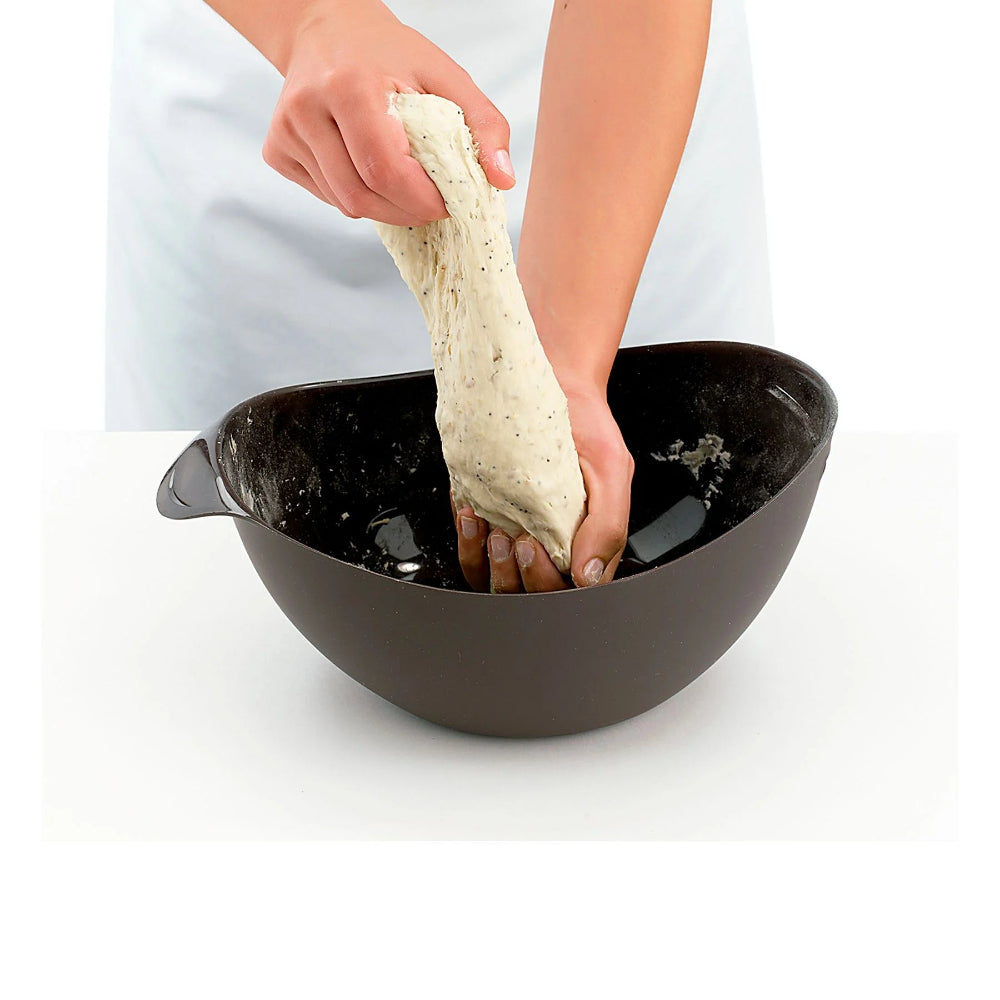 Person kneading dough in a black plastic bowl 