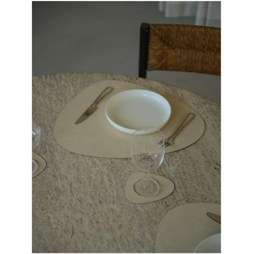 Dining table setting with heart-shaped placemats, plates, and cutlery on a textured surface.
