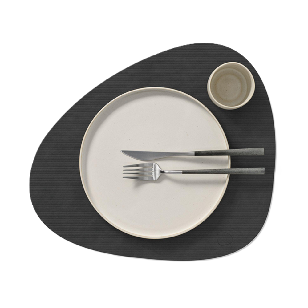 Dinner setting with a white plate, knife, fork, and small bowl on a black placemat.