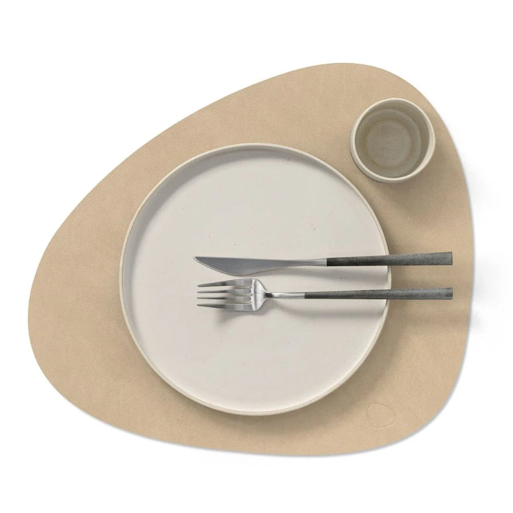 Beige placemat with a plate, knife, and fork on a white background